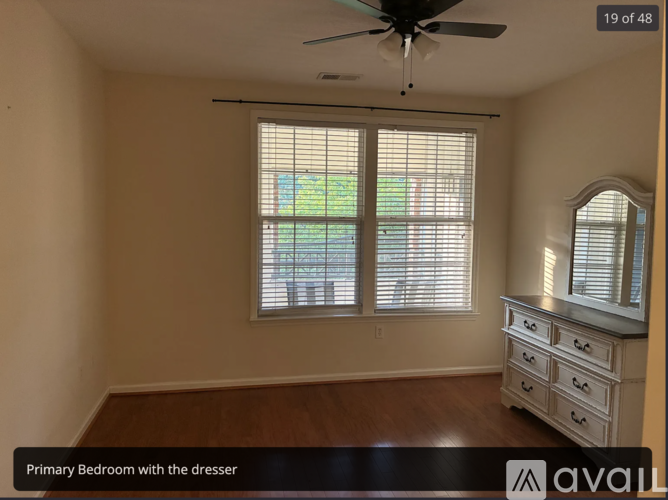 A bedroom with a dresser and a window with blinds.