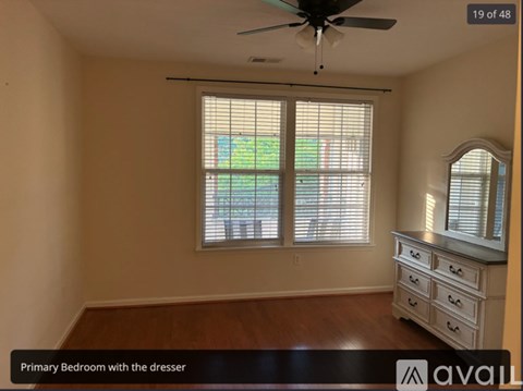 A bedroom with a dresser and a window with blinds.
