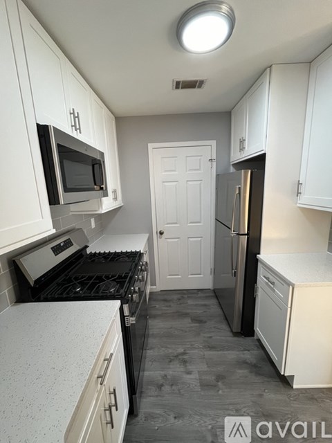 A kitchen with white cabinets and a black stove top oven.