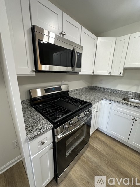 A kitchen with a black stove top oven and white cabinets.