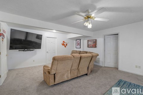 A living room with a beige couch and a ceiling fan.