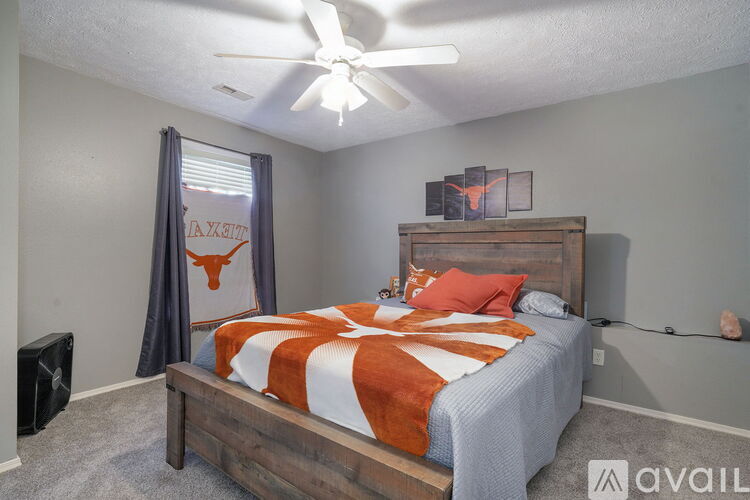 A bedroom with a bed, a ceiling fan, and a Texas Longhorns flag.