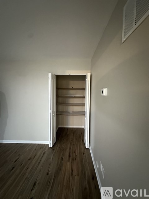 A room with a white wall and a wooden floor with a white door.
