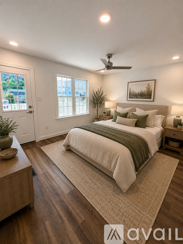 A bedroom with a large bed, a ceiling fan, and a view of the outdoors through the window.