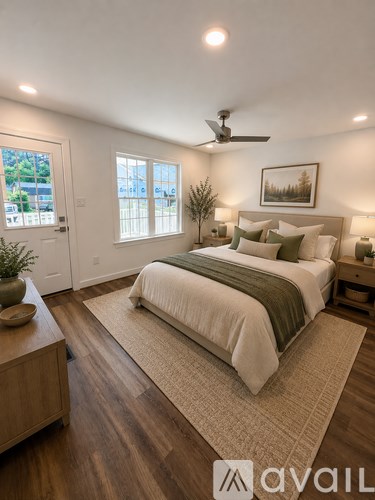 A bedroom with a large bed, a ceiling fan, and a view of the outdoors through the window.