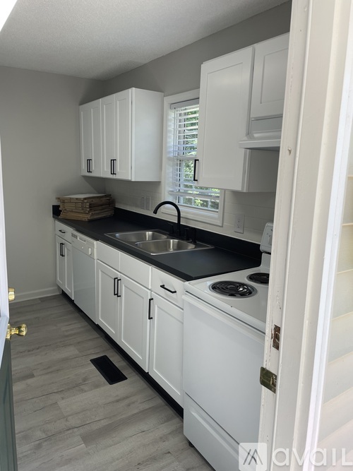 A kitchen with white cabinets and a black countertop.