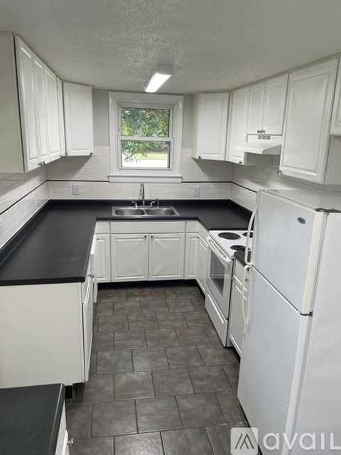 A kitchen with white cabinets and black countertops.