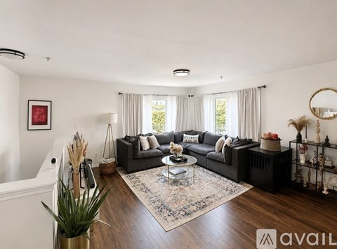 A living room with a black sofa and a rug.