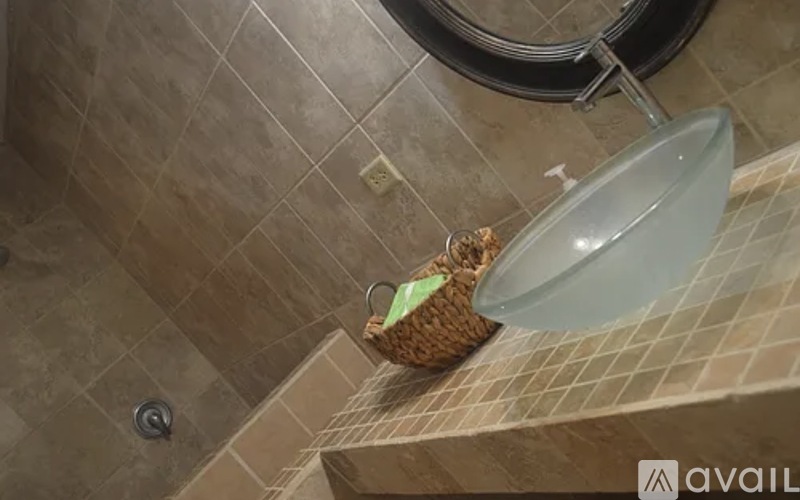 A shower with a glass door and a basket on the edge.