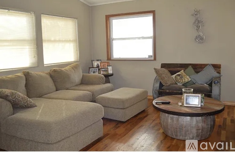 A living room with a grey sofa, a wooden coffee table, and a large window.