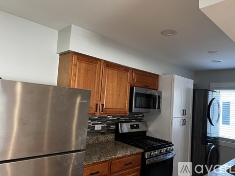 A kitchen with a stainless steel refrigerator, microwave, oven, and black dishwasher.