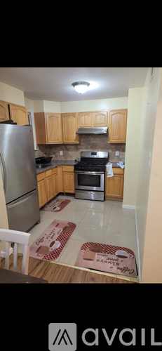 A kitchen with wooden cabinets and a stainless steel refrigerator.
