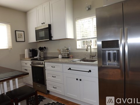 A kitchen with white cabinets and a stainless steel refrigerator.