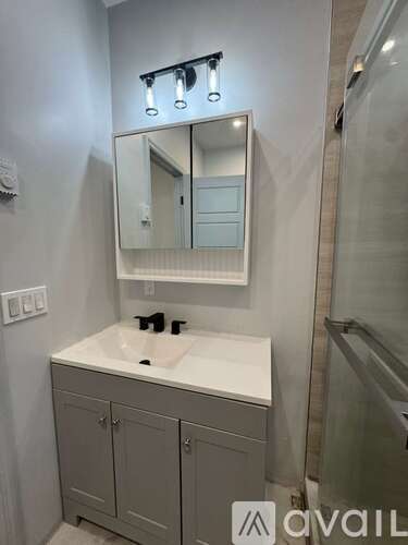 A bathroom with a sink, mirror, and cabinet.