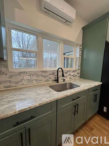 A kitchen with a marble countertop and green cabinets.