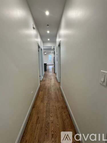 A long hallway with wood floors and white walls.