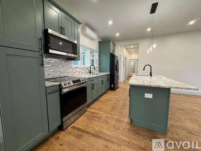 A kitchen with green cabinets and a marble island.