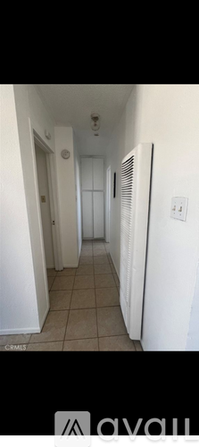 A long hallway with a white door and a white refrigerator.