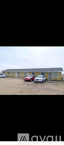 A yellow building with a red car parked in front.