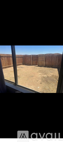A view from inside a vehicle looking out to a fenced yard.