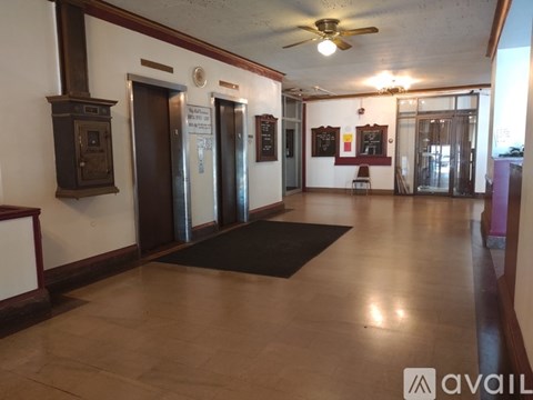 A hallway with a black mat on the floor and a ceiling fan.