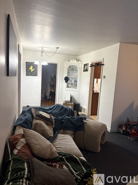 A living room with a couch covered in blankets and pillows.