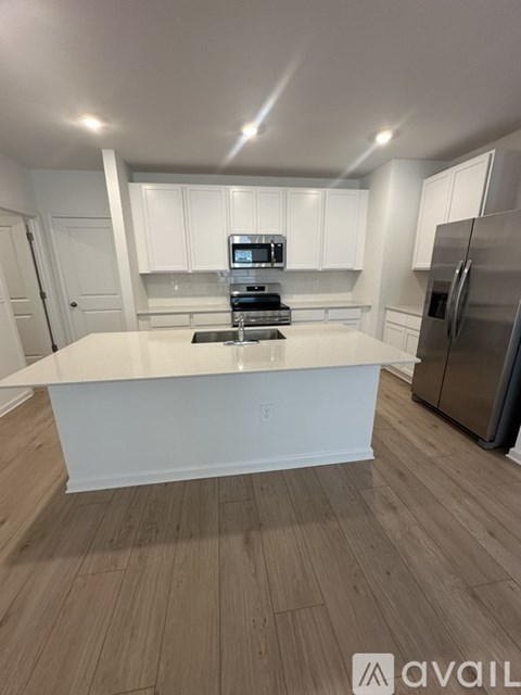 A kitchen with white cabinets and a wooden floor.
