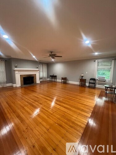A spacious room with wooden flooring and a fireplace.