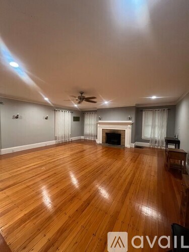 A spacious room with wooden flooring and a fireplace.