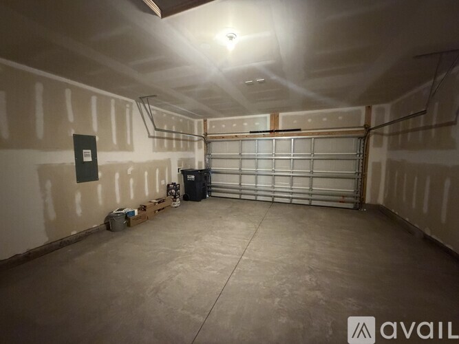 A spacious garage with a concrete floor and a metal gate.