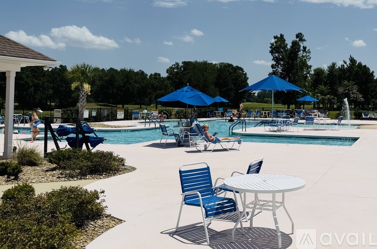 A pool area with blue chairs and umbrellas.