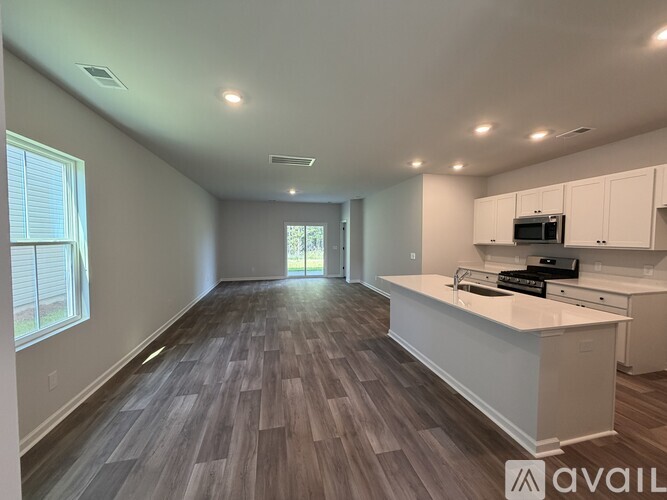 A spacious kitchen with white cabinets and a wooden floor.