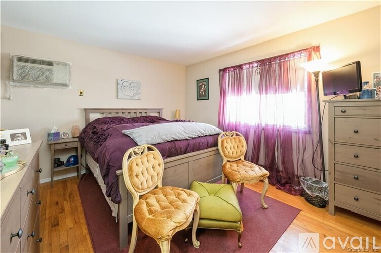 A bedroom with a bed, chair, and a window with curtains.