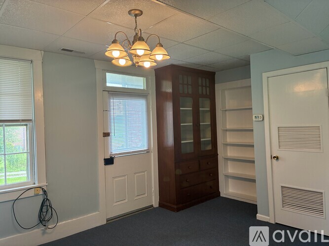 A room with a wooden cabinet, a window with blinds, and a door with a number 13 on it.