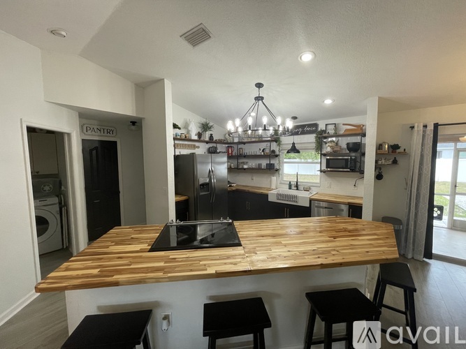 A kitchen with a wooden table and black stools.