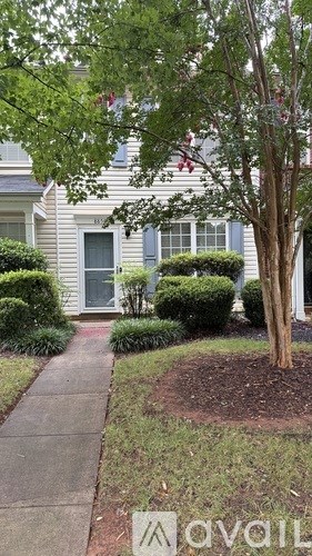 A tree in a yard in front of a house.