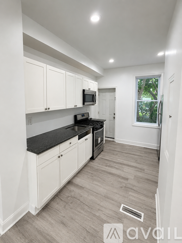 A kitchen with white cabinets and a black countertop.