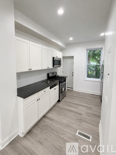 A kitchen with white cabinets and a black countertop.