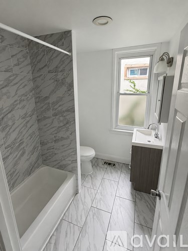 A bathroom with a marble tile shower and a white bathtub.