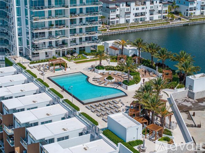 A large swimming pool surrounded by palm trees and lounge chairs in a resort setting.