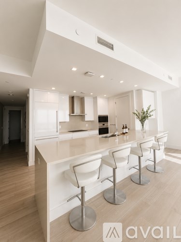 A modern kitchen with white chairs and a wooden floor.
