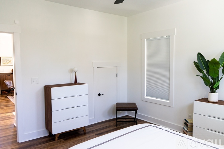 A white bedroom with a dresser and a window.