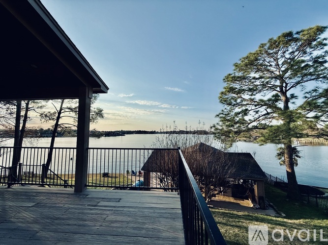 A balcony overlooks a body of water with a tree and a building in the distance.