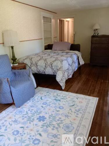A bedroom with a bed, a chair, and a dresser.