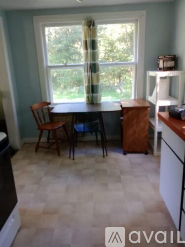 A kitchen with a table and chairs by a window.