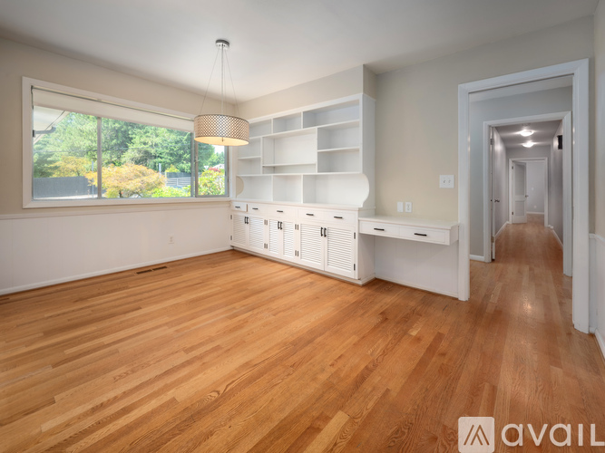 A spacious room with wooden floors and a large window.