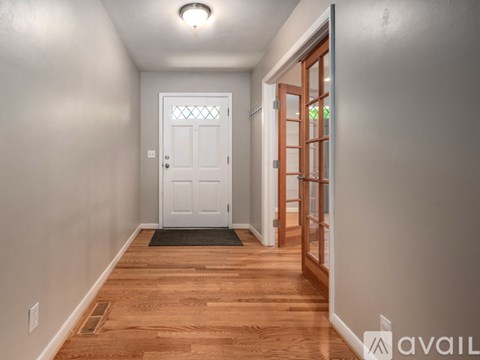 A hallway with a white door and wooden floors.