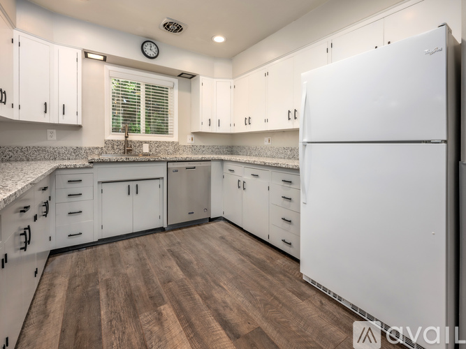 A kitchen with white cabinets and a white refrigerator.