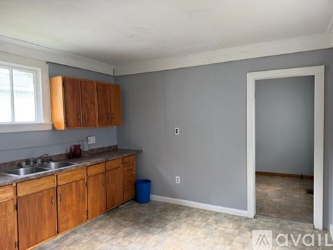 A kitchen with wooden cabinets and a blue trash can.
