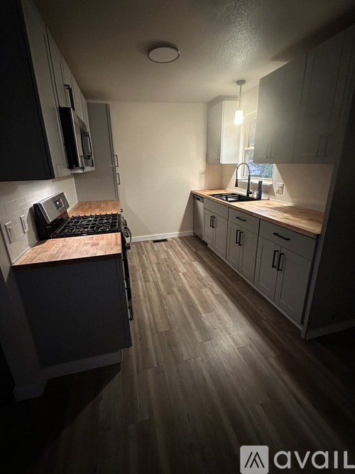 A kitchen with wooden floors and a stove top oven.
